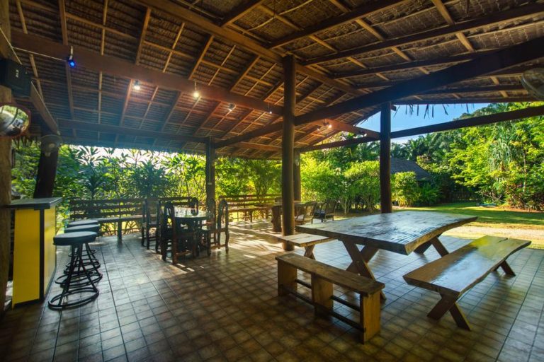 a roofed dining area in tropical gardens