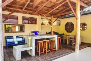 In a courtyard of a villa, covered decking and furniture, bar and stools