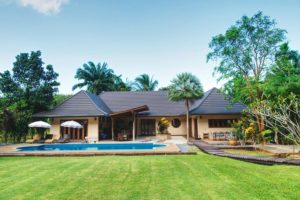 A villa with courtyard and swimming pool set in tropical gardens with grass lawn